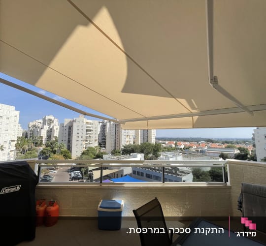מרפסת עם סוכך פתוח ונוף עירוני ברקע